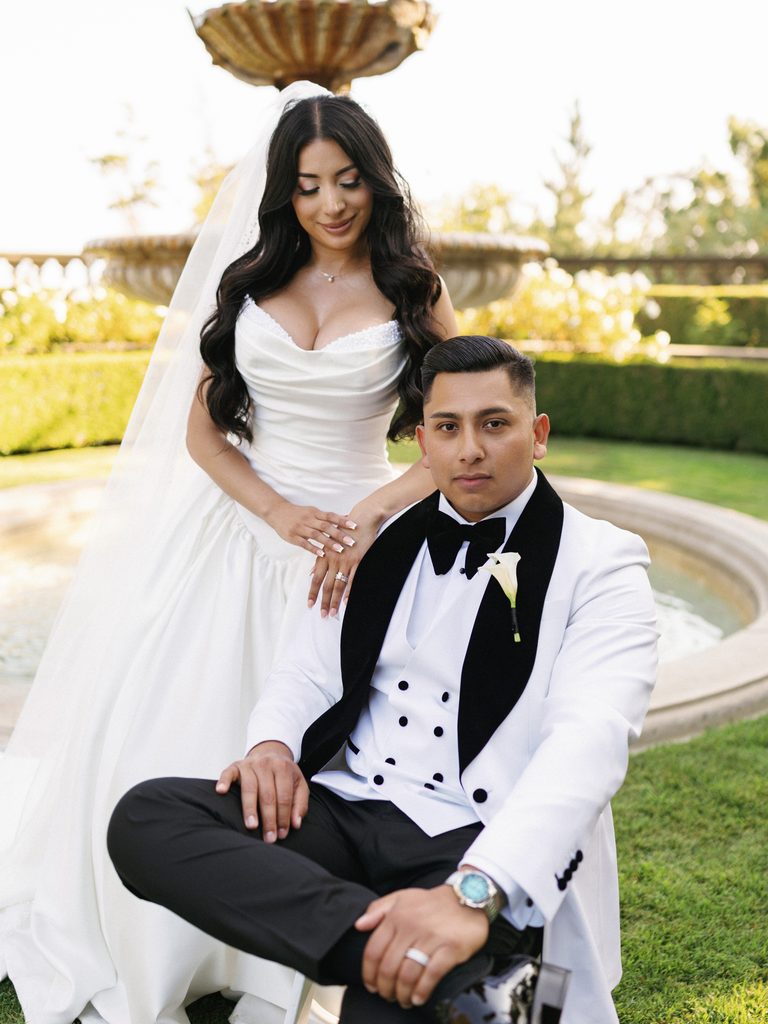 Sophisticated couple posing near a historic stone fountain during portrait hour