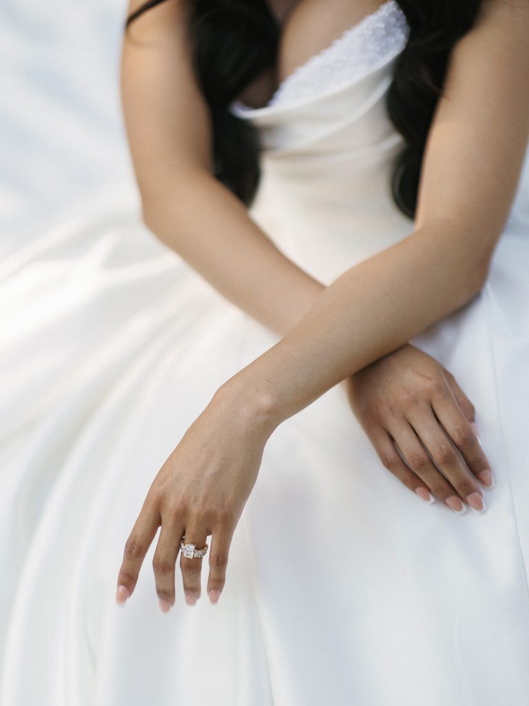 Macro shot of premium bridal jewelry resting on a white silk wedding dress bodice