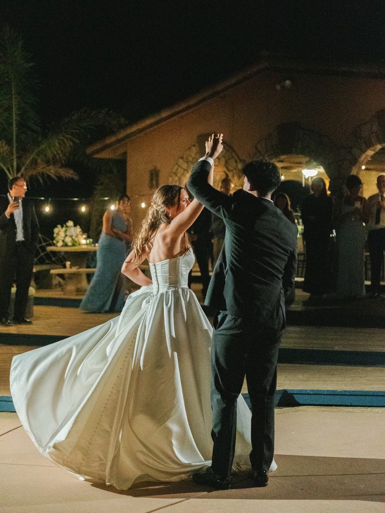 Bride and groom sharing their first dance under warm wedding reception lighting at night.
