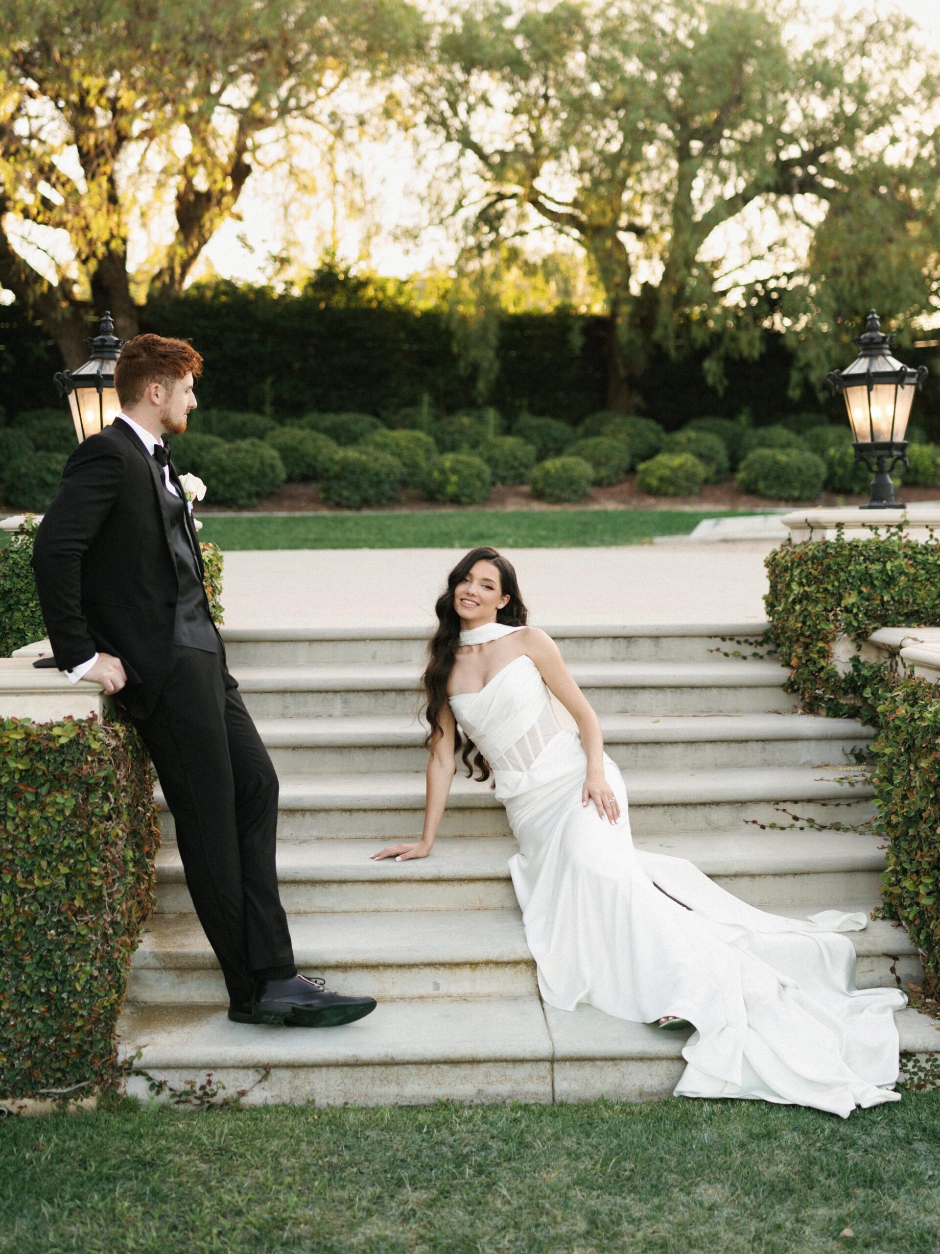 Sophisticated newlyweds posing on outdoor stone stairs at a luxury garden estate, illustrating a guide on how to choose a wedding photographer.