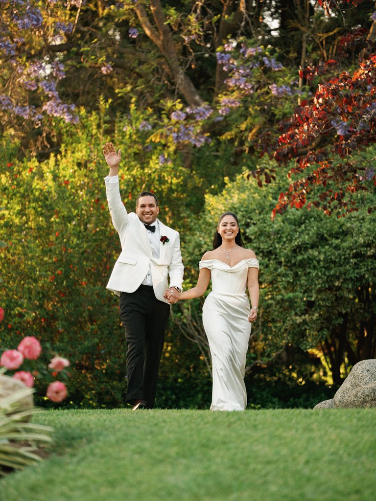 Joyful wedding reception photos showing a newlywed couple walking into their outdoor celebration while waving to guests.