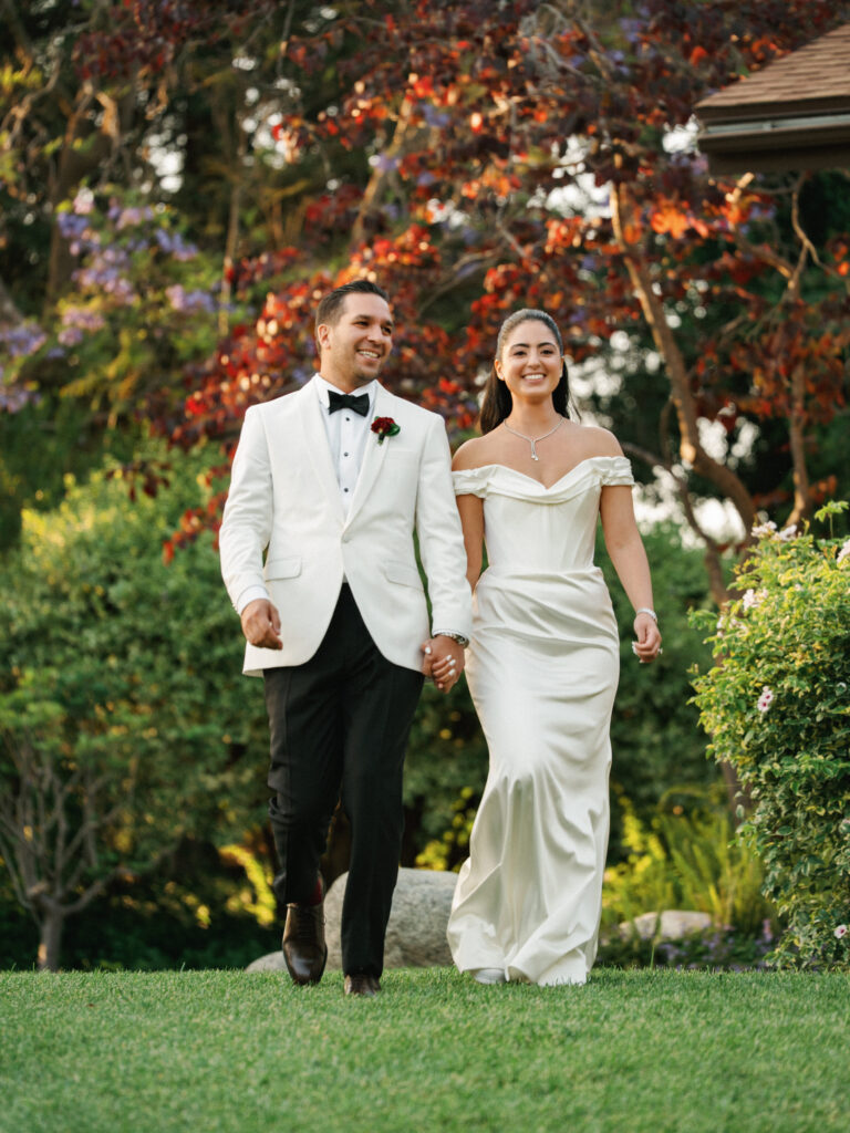 Candid wedding reception photos of a bride and groom holding hands during their grand entrance.