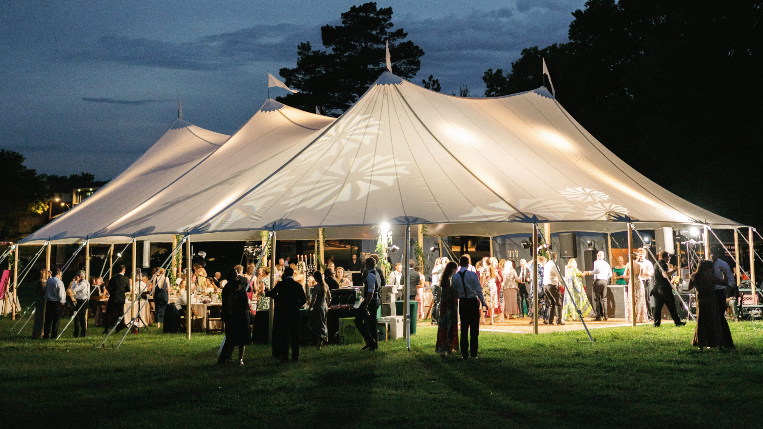 Luxury wedding reception lighting inside an elegant outdoor tent at night.