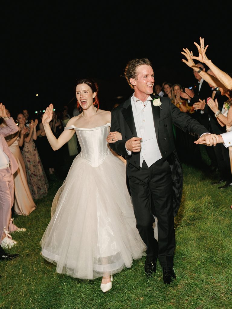 Bride and groom celebrate their exit under dramatic night wedding reception lighting.