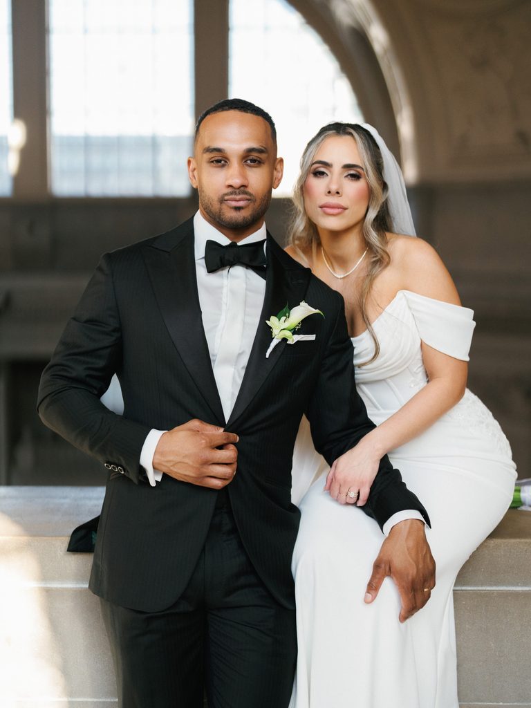 High-fashion bride and groom posing confidently inside the iconic San Francisco City Hall, illustrating editorial wedding photography styles.
