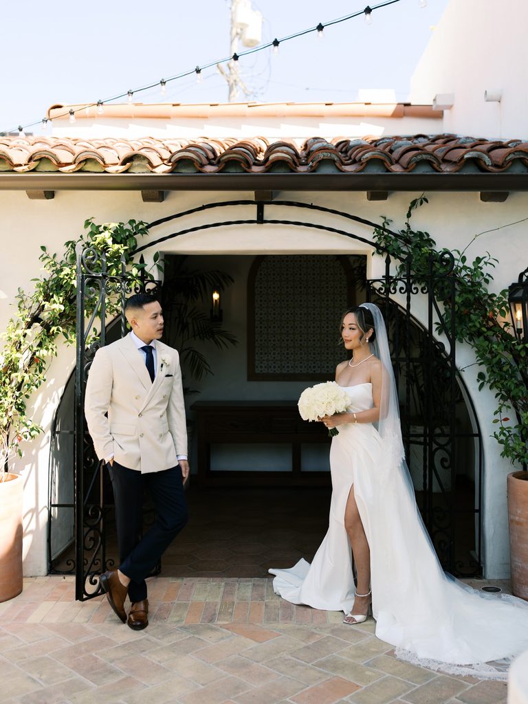 Luxury bride holding a white rose bouquet near an elegant courtyard archway