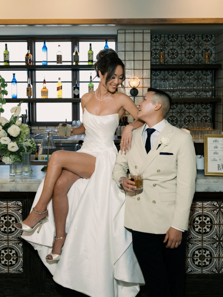 Trendy bride and groom posing at a luxury cocktail bar, showcasing modern and fun wedding photography styles.
