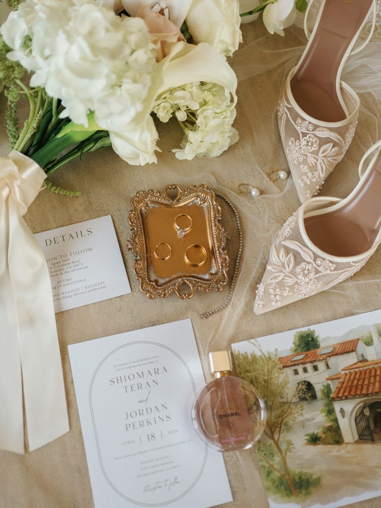 Luxury bridal flat lay featuring elegant lace heels and Chanel perfume with custom invitation cards