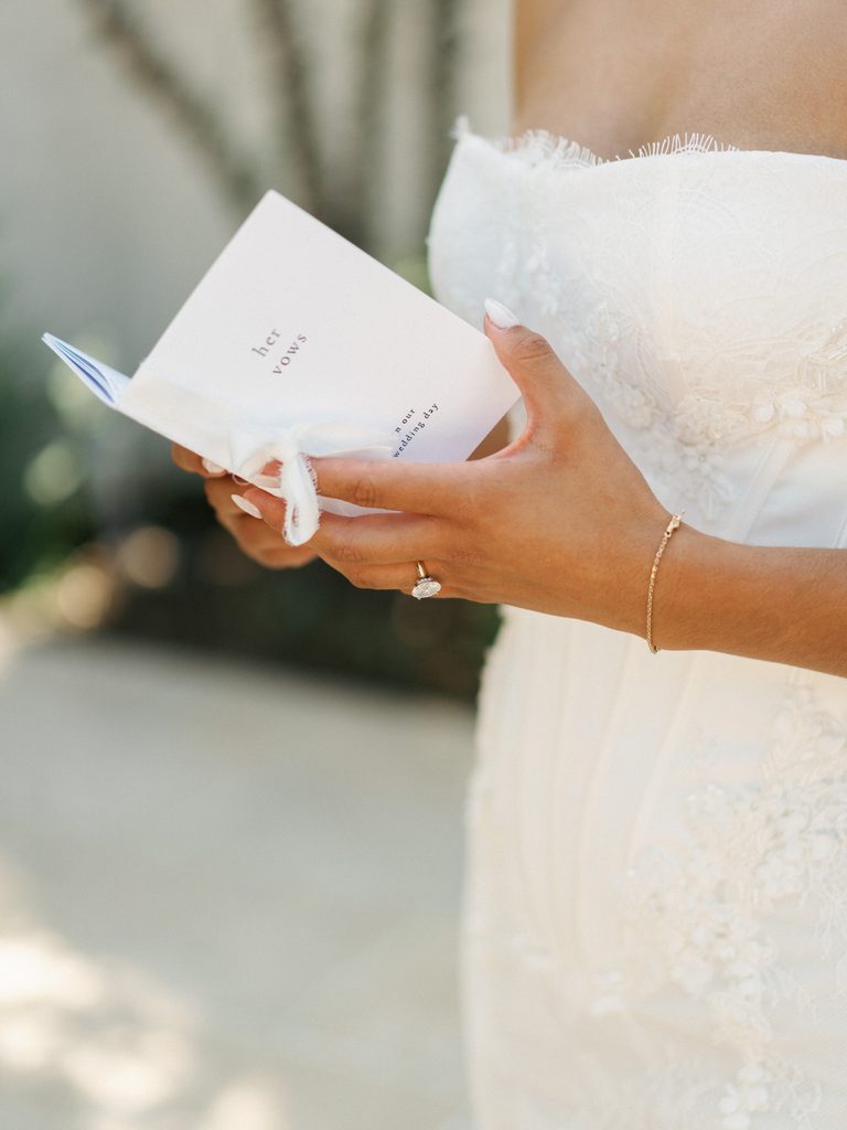Close up of a luxury bride holding a white her vows book before ceremony
