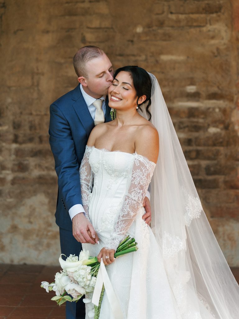 Romantic newlyweds sharing an intimate moment outside a historic estate villa