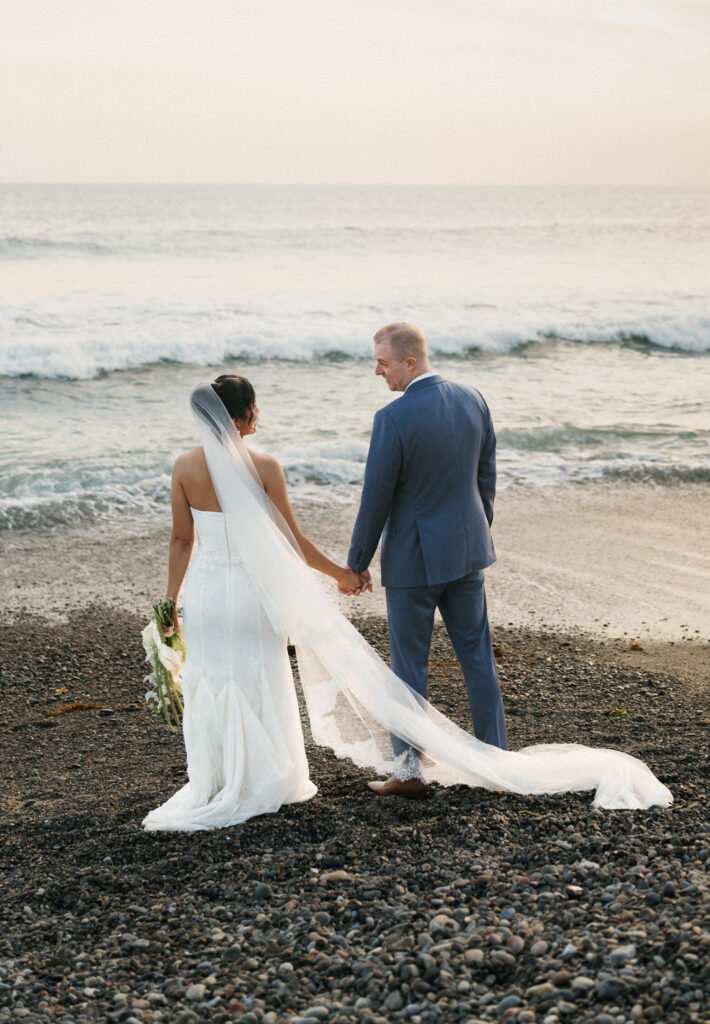 Full length beach wedding couple portrait showcasing a long cathedral veil with trim