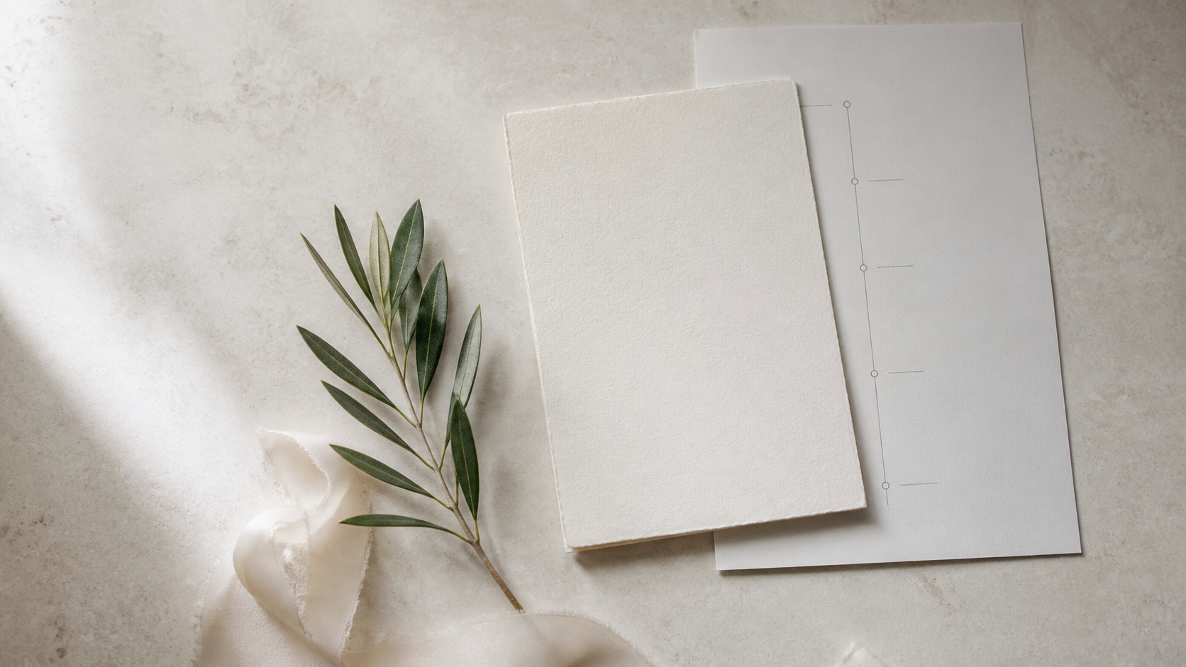 Ivory planning card, olive branch, and a simple timeline sheet on stone