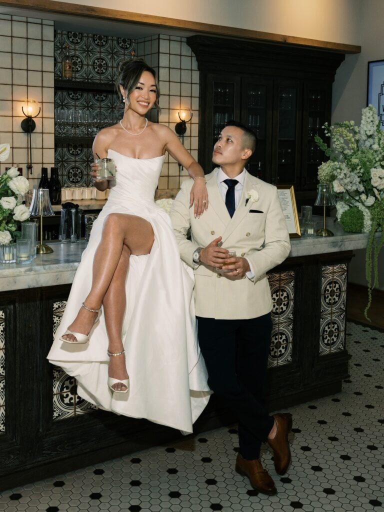 Newlyweds pose together at an indoor reception bar