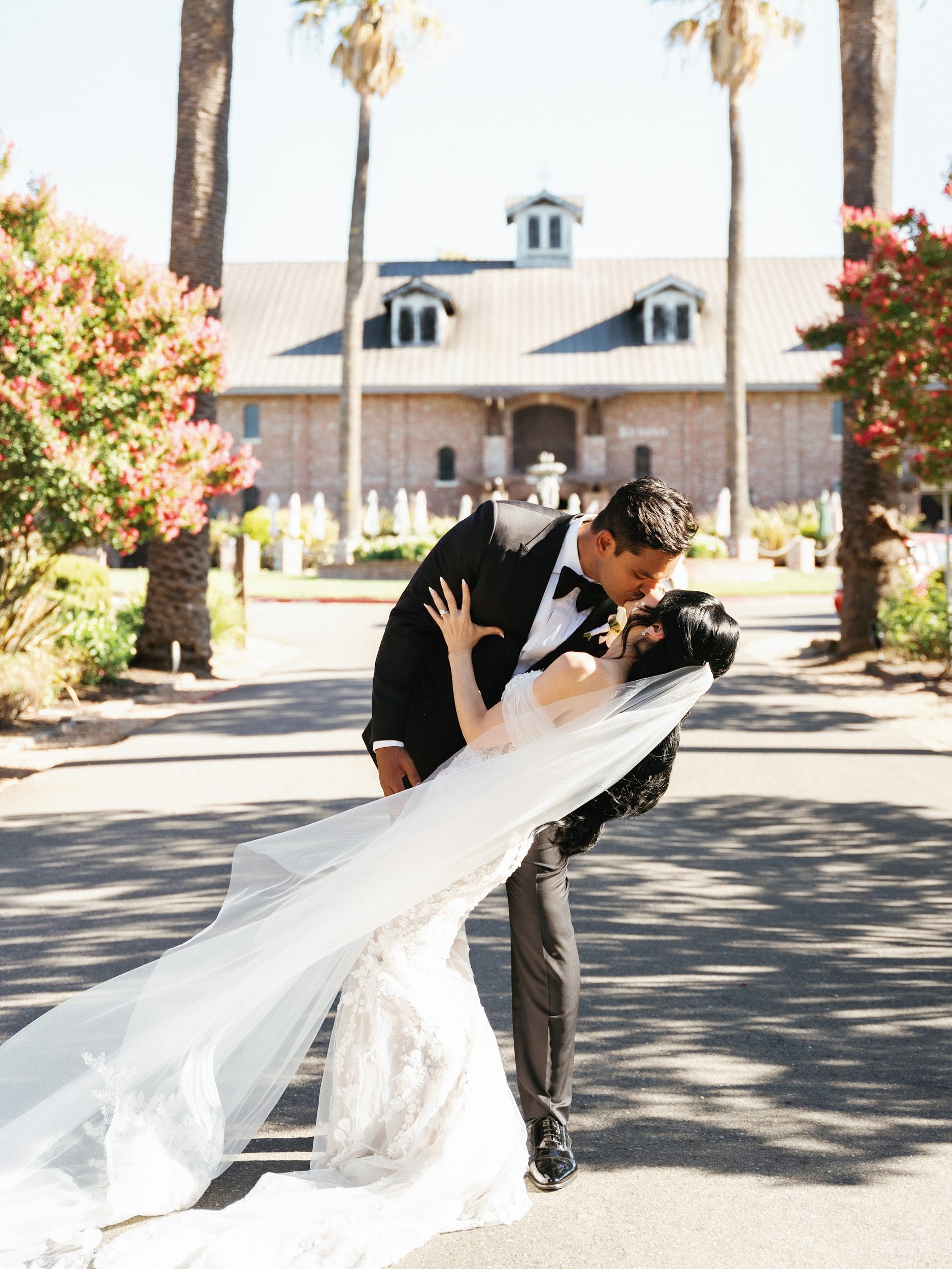 Newlyweds share a dip in front of a sunlit wedding venue