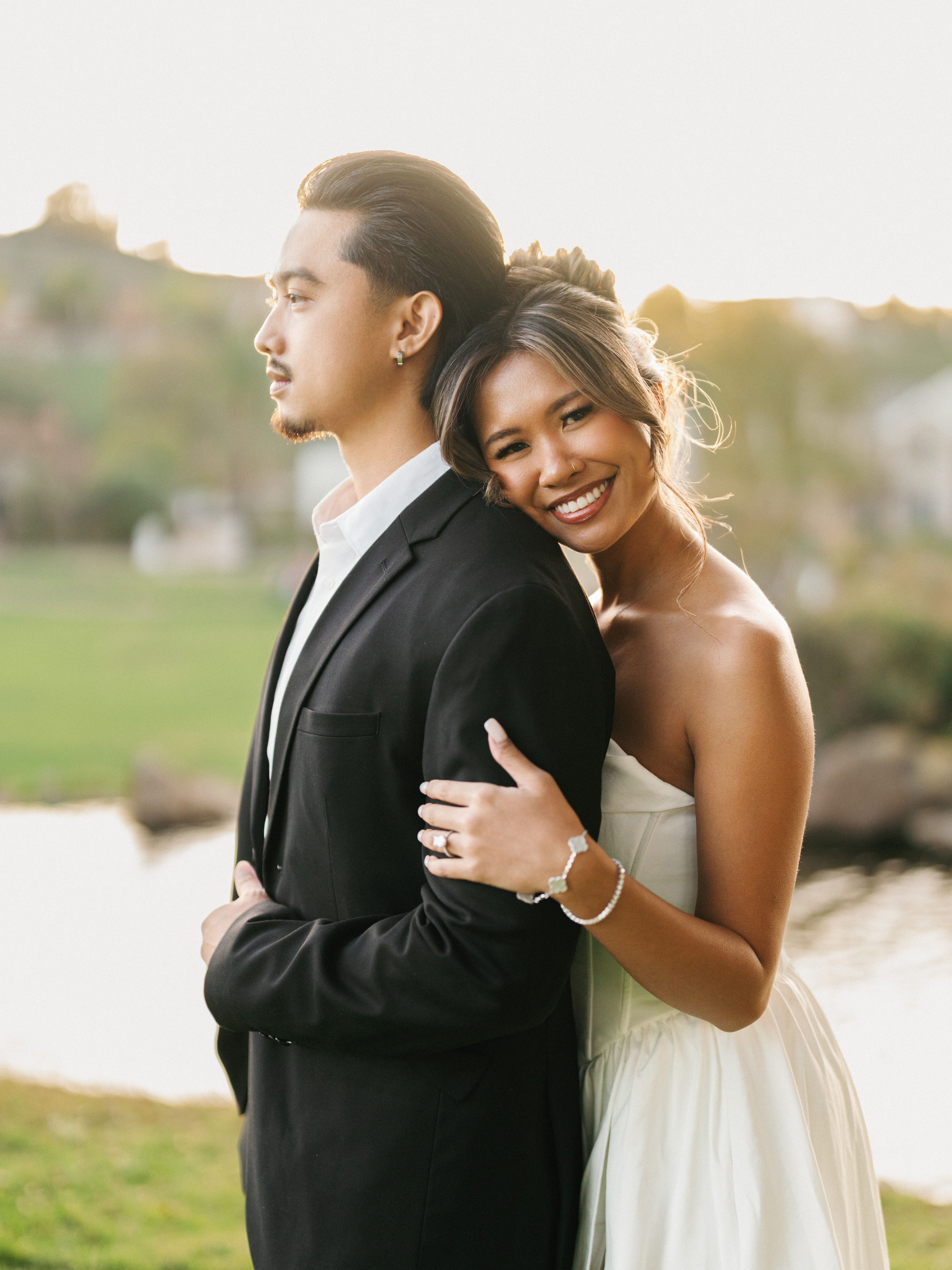 Golden hour couple portrait featuring a radiant bride leaning on grooms shoulder holding his arm during a luxury outdoor sunset session