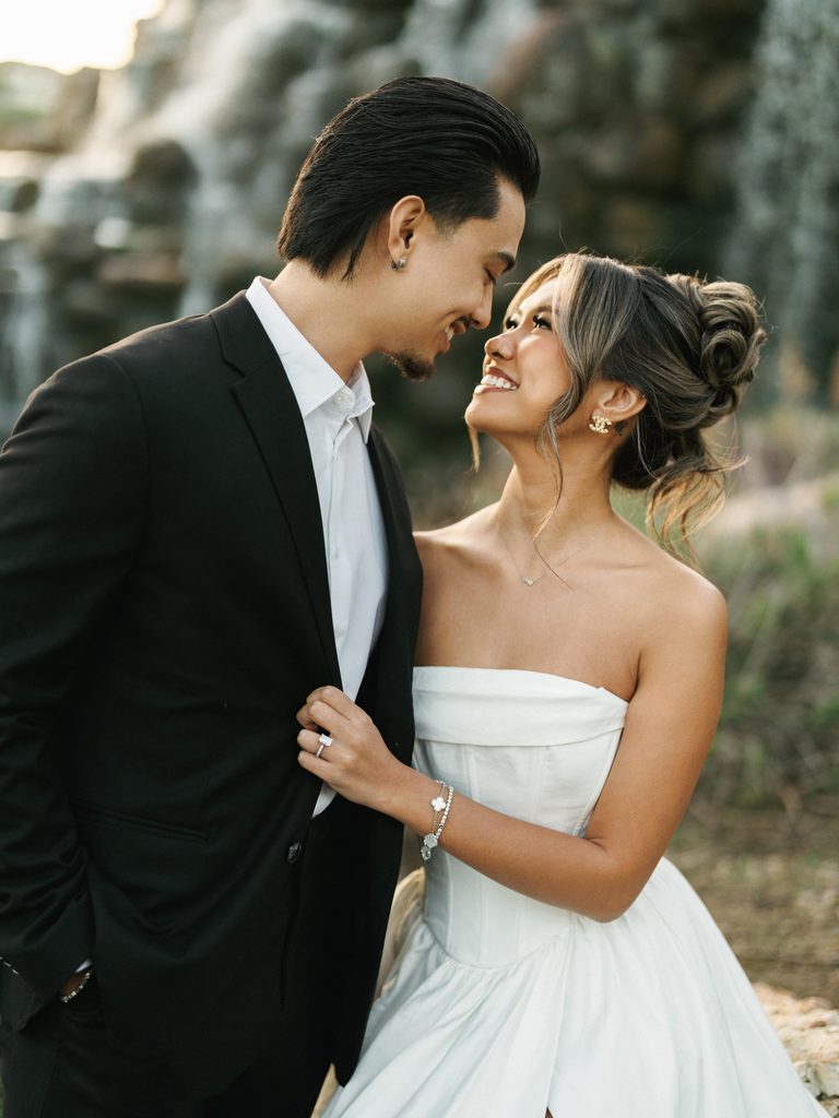 Romantic bridal portrait of a couple smiling looking at each other featuring gorgeous gold chanel logo earrings and a modern high bun updo