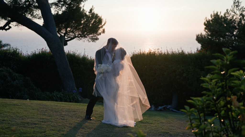 A bride and groom share a private moment under a sheer veil at golden hour, overlooking the Pacific Ocean at La Venta Inn in Palos Verdes Estates.