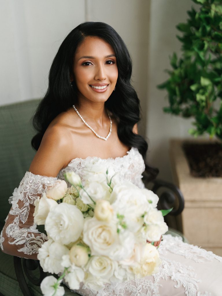 Sophisticated brunette bride smiling for a close up portrait with timeless hollywood waves hairstyle holding a lush white rose bouquet