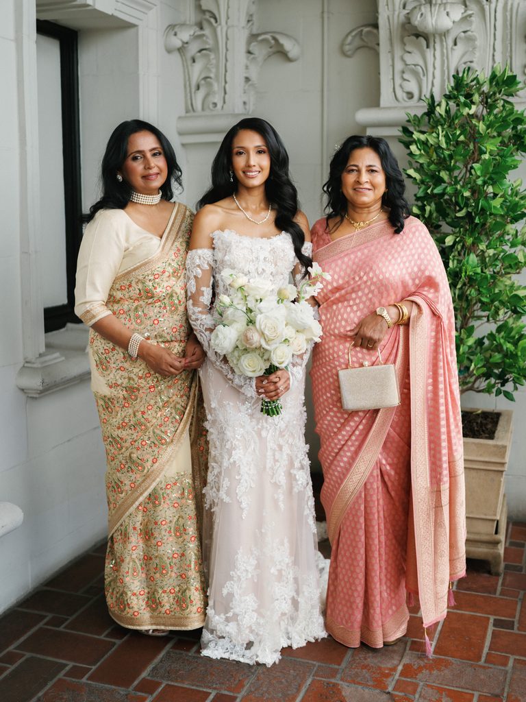 Sophisticated bridal family portrait with gorgeous women wearing traditional embellished indian sarees in pink and gold tones
