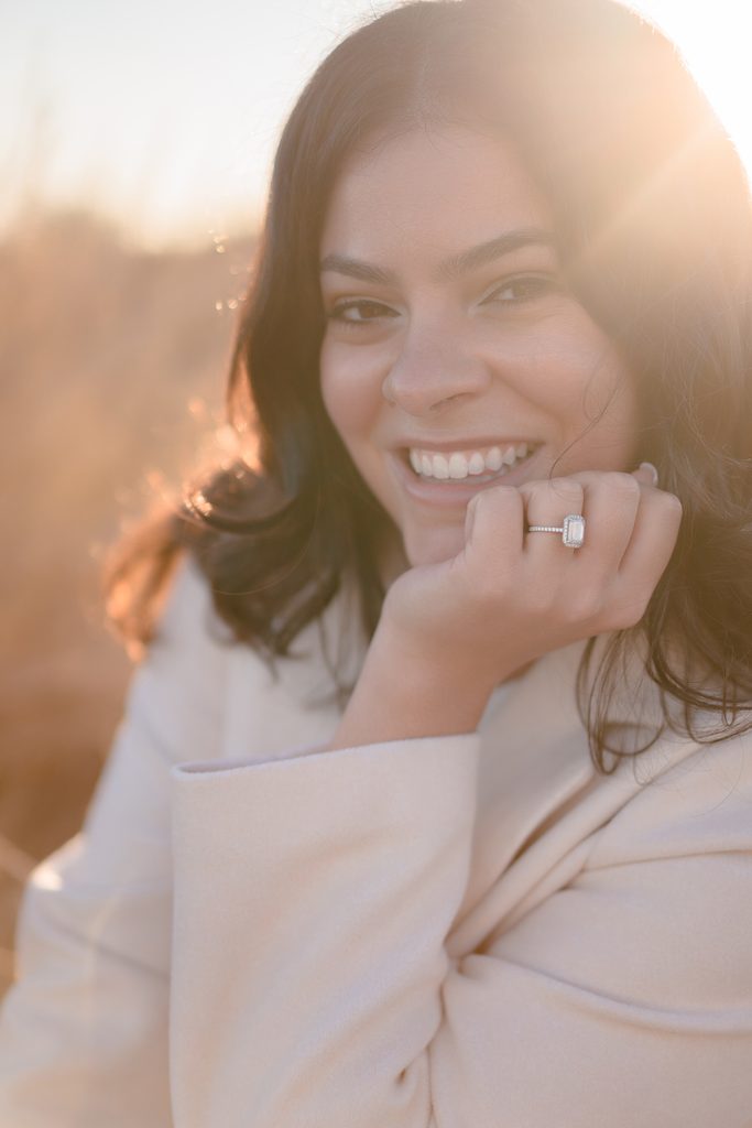 Close-up portrait highlighting a diamond ring and a cozy cream coat, inspiring winter engagement photo outfits.