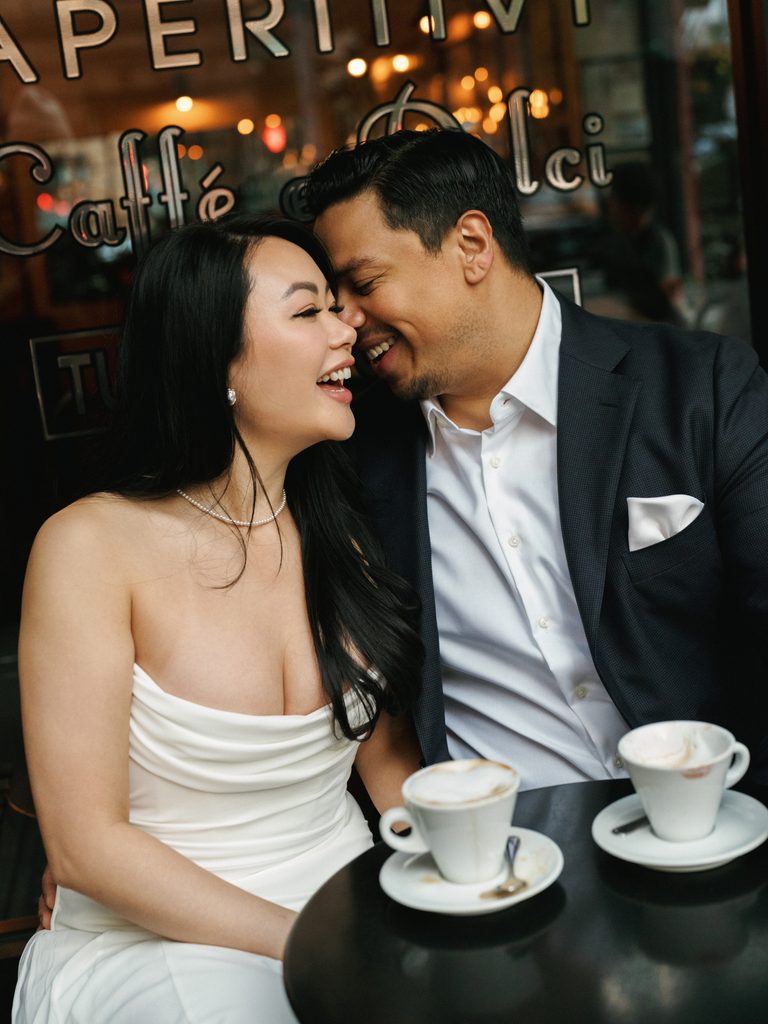 Close-up portrait of a couple laughing at an Italian cafe table, inspiring cozy restaurant engagement photo ideas.
