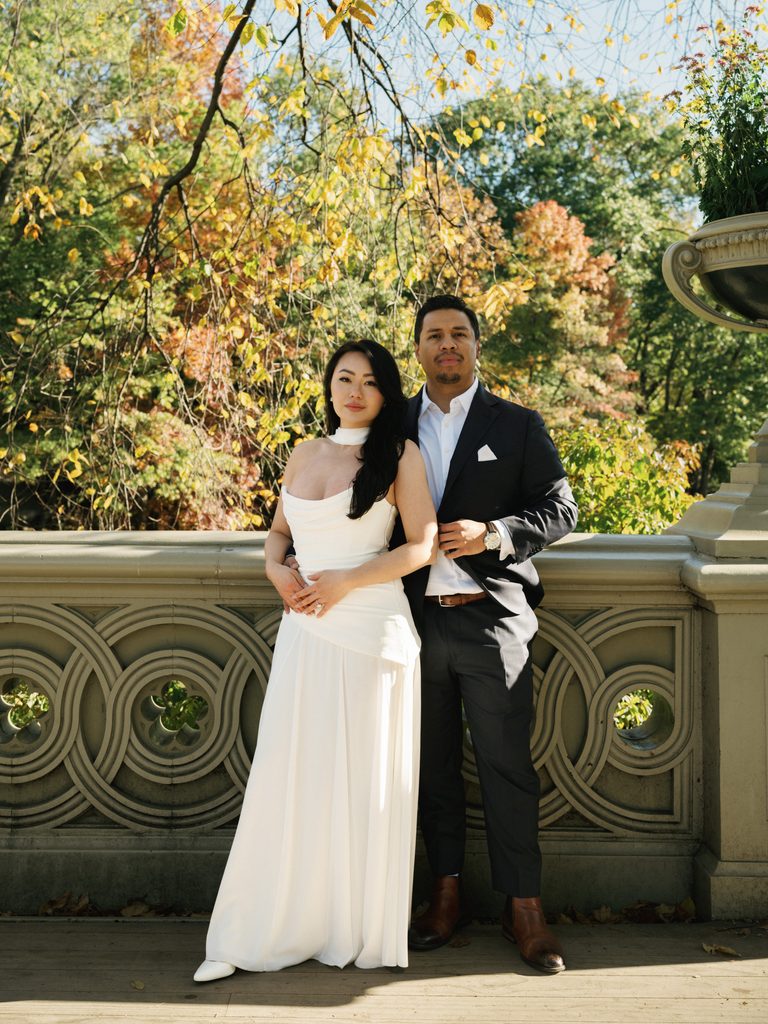 Elegant couple posing by Bow Bridge stone railing showcasing classic New York engagement photo ideas