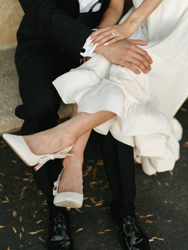 Close-up of white bridal heels and black dress shoes, inspiring elegant engagement photo outfits.