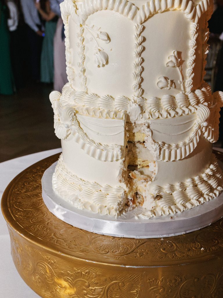 Close up of an elegant luxury wedding cake with intricate white buttercream piping details and delicate floral patterns
