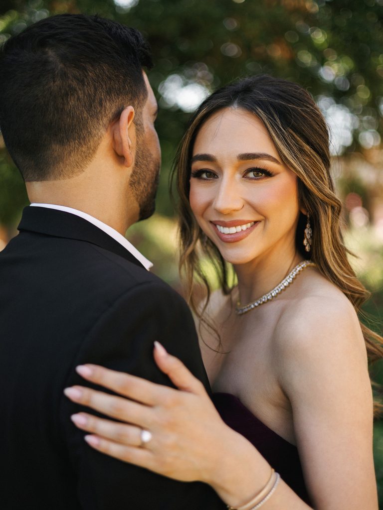 Bride-to-be in a strapless dress looking back at the camera, showcasing elegant jewelry for engagement photo outfits.