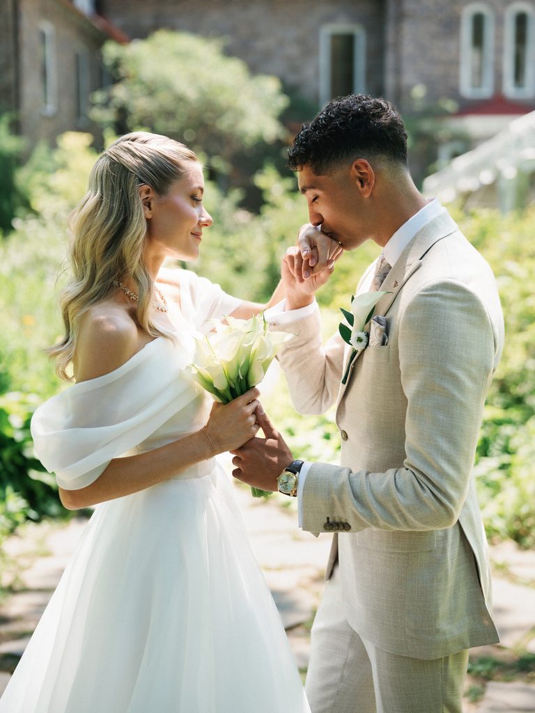 Groom tenderly kisses the brides hand during a romantic outdoor portrait session illustrating natural wedding photo poses