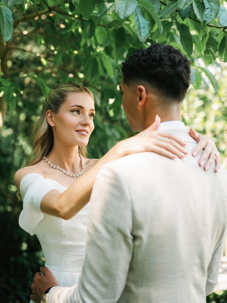 Bride looks lovingly at her groom with her hands resting elegantly on his shoulders
