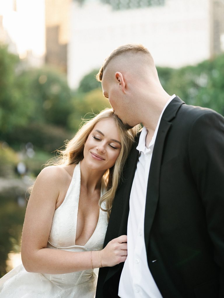 Groom-to-be kissing the head of his bride-to-be in a halter dress, inspiring romantic engagement photo outfits.