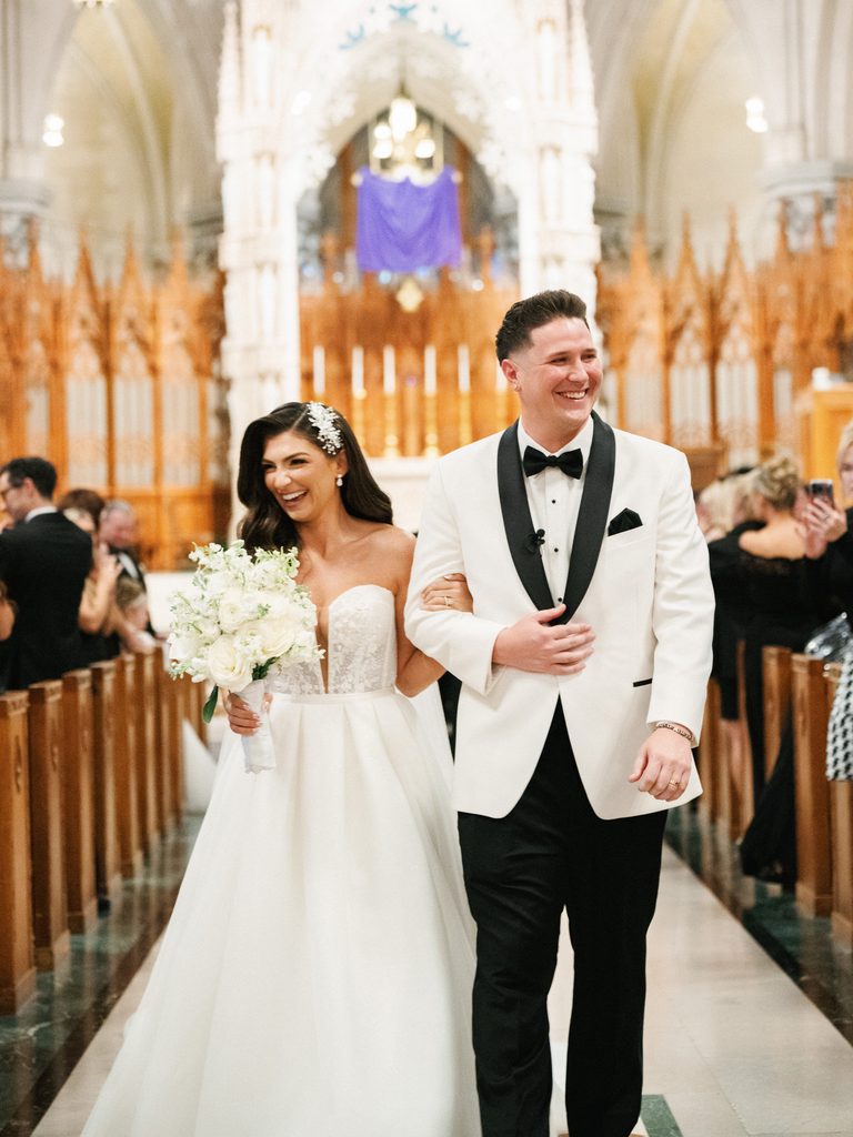Joyful bride and groom walking down the aisle during a luxury church ceremony matching terms defined in a wedding photographer contract
