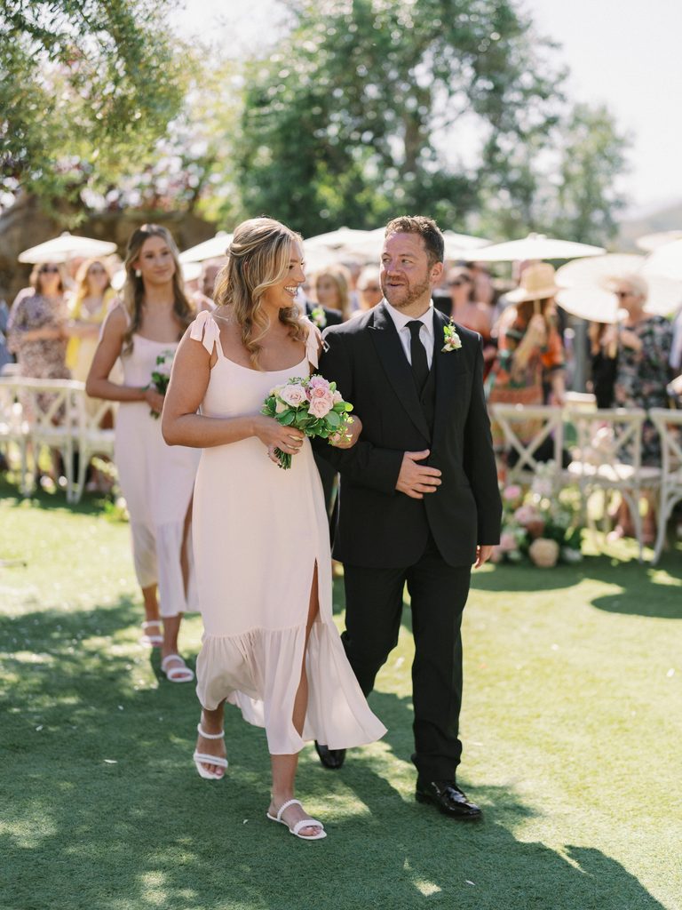 Bridesmaid and groomsman smiling while walking down the aisle, featured in a professional wedding photo gallery.