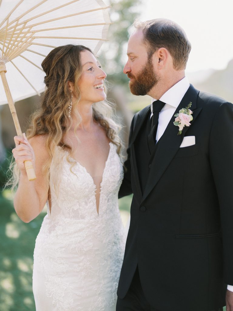 Elegant couple portrait with a parasol, showcasing timeless style for a luxury wedding photo gallery.