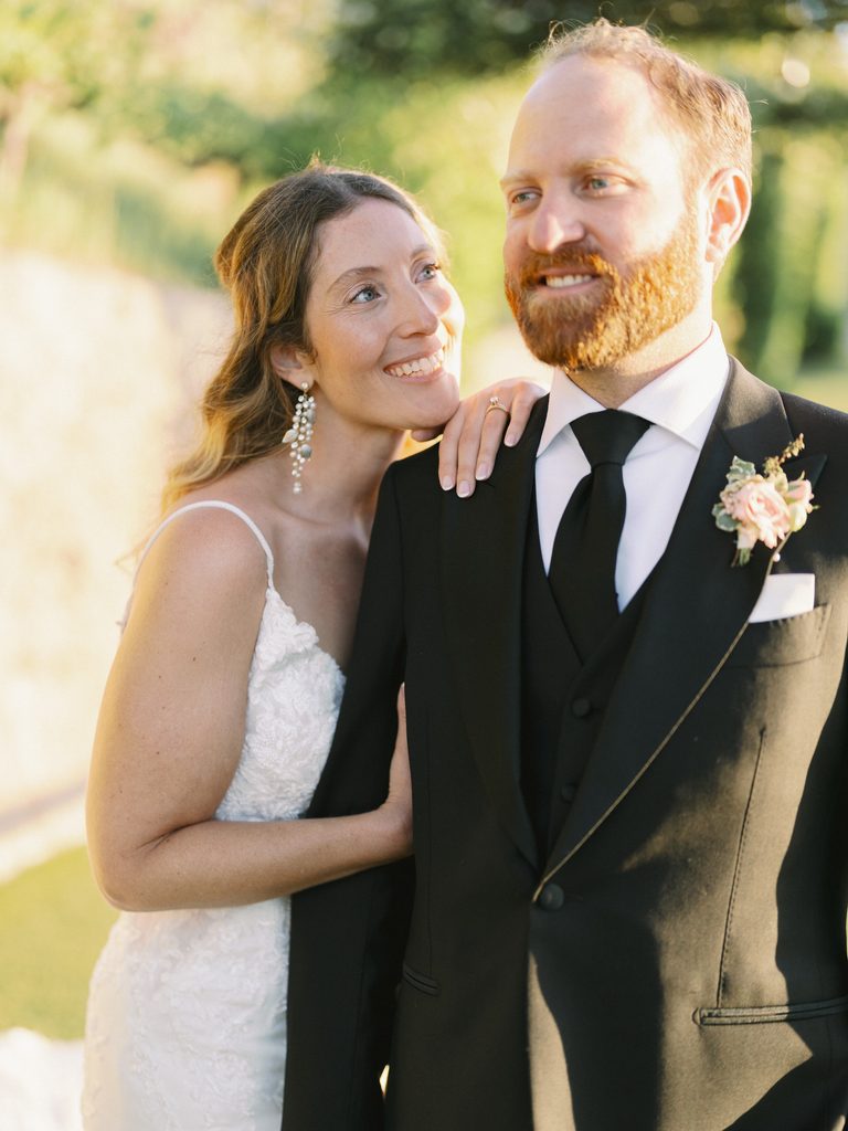 Bride leaning on her groom's shoulder and smiling warmly during a sunset session.