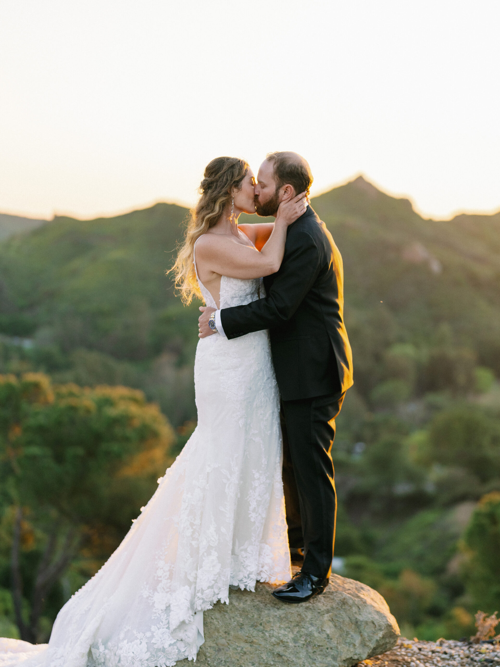 Sunset kiss on a cliffside, highlighting the epic portraits in a premium wedding photo gallery.