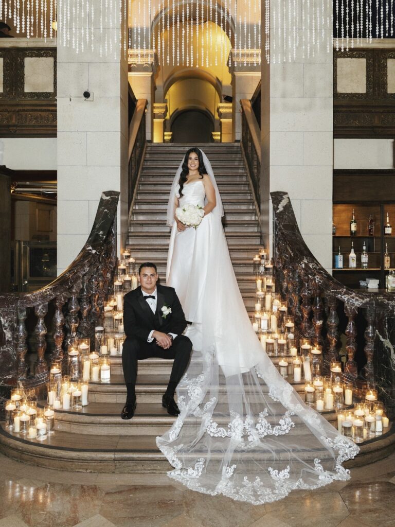 Couple posed on a candlelit staircase.
