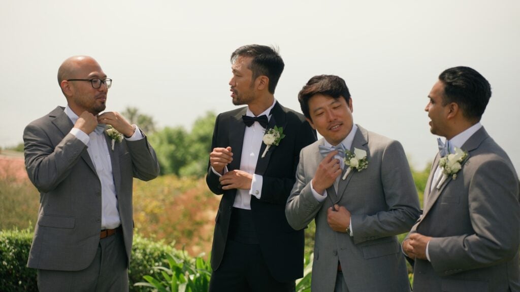 Groomsmen adjusting their bow ties and suits before the ceremony.