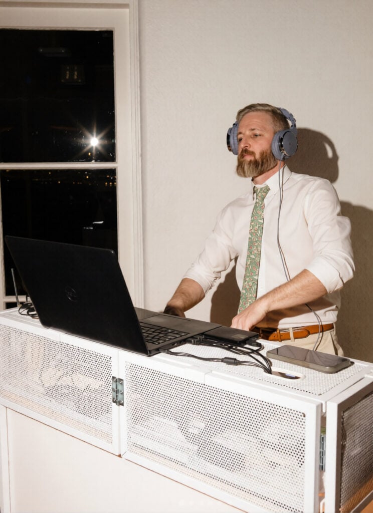 Diego Hellewell of VOX DJs managing the music playlist on a laptop during a reception