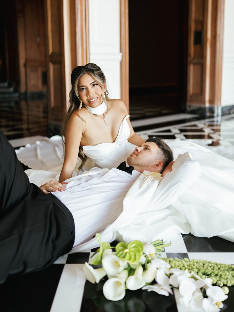 Chic couple posing on glossy tiled floor featuring voluminous white wedding dress and dinner jacket