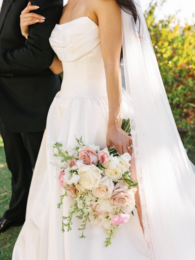 Close up of bride holding romantic wedding bouquet with blush pink roses and white delphiniums