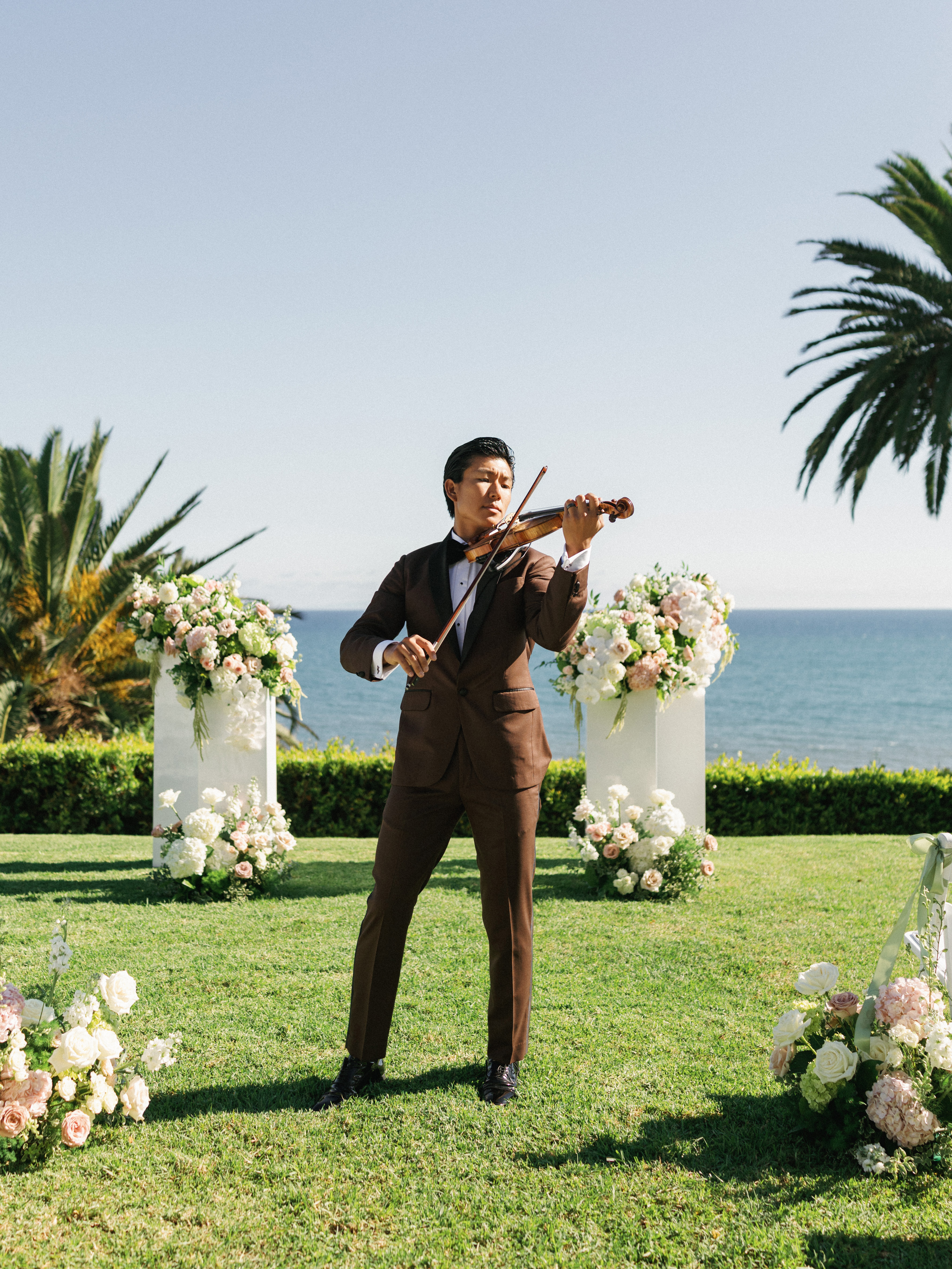 Talented violinist playing music outdoors during luxury wedding ceremony overlooking the ocean