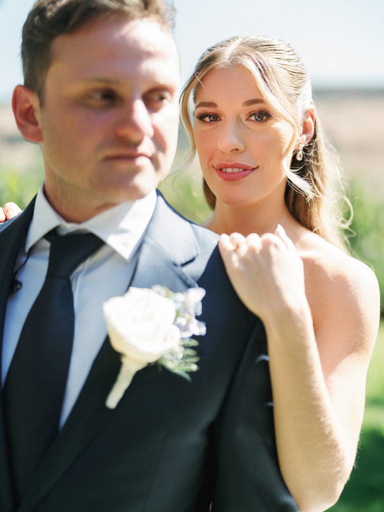 Close up portrait of beautiful blonde bride leaning on groom behind his back