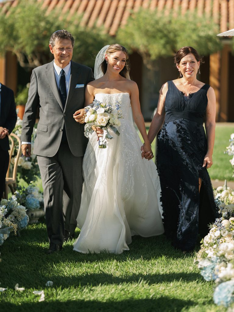 Bride walking down the aisle with mother and father at luxury destination wedding