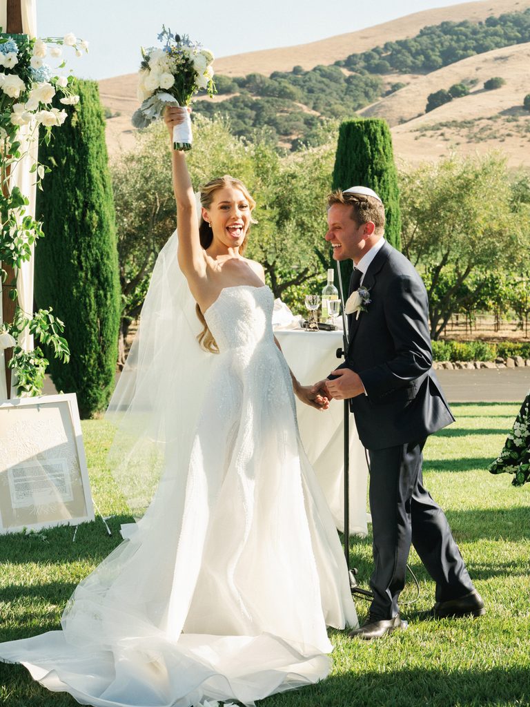 Excited newlyweds celebrating right after outdoor wedding ceremony at California vineyard venue