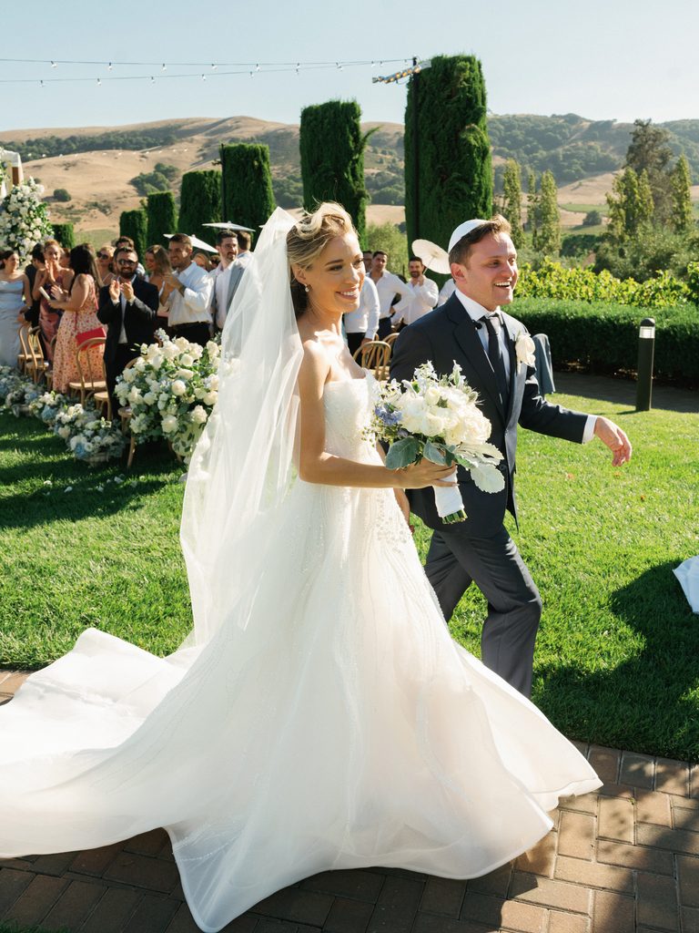 Newlyweds walking down the aisle after ceremony at luxury California vineyard wedding