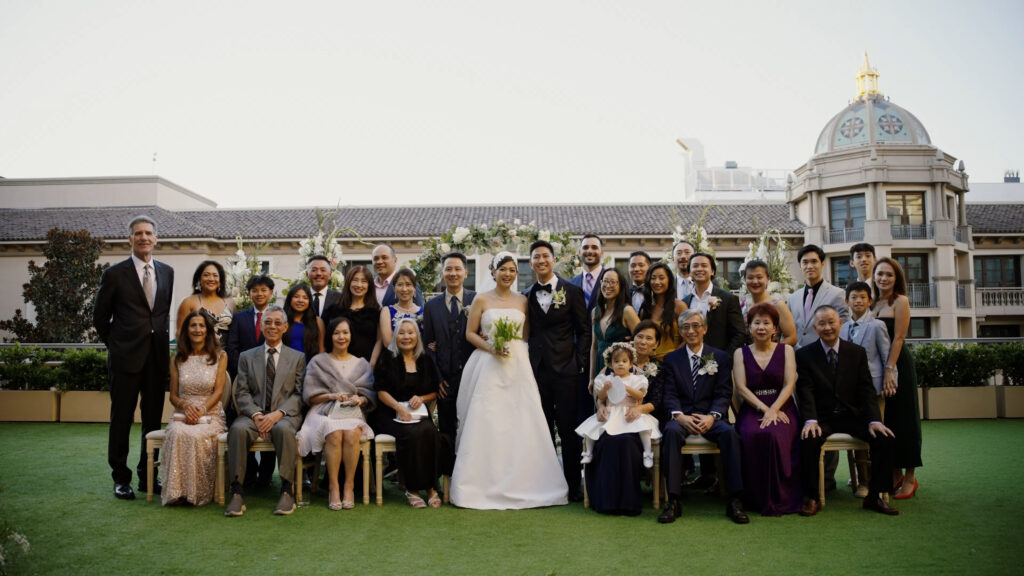 A formal wedding portrait with family and friends at The Maybourne Beverly Hills, with the venue's architecture in the background. Dreamwood wedding photography and Stephy Plechas.