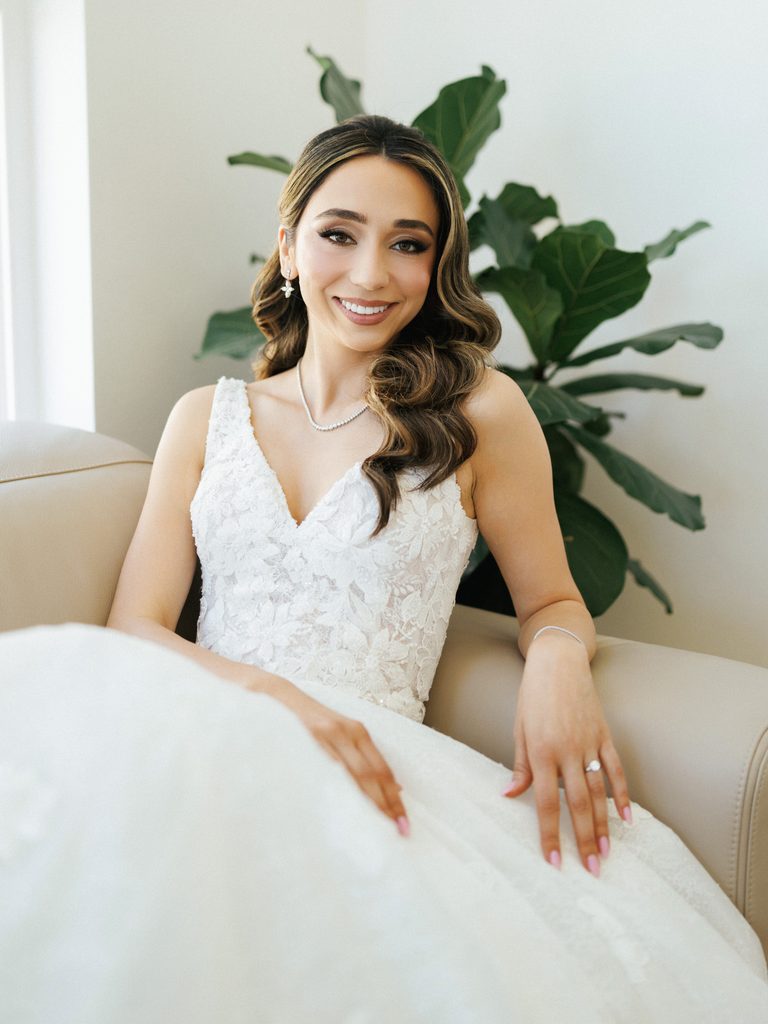 Stunning bride posing in V neck sleeveless wedding dress featuring delicate floral embroidery