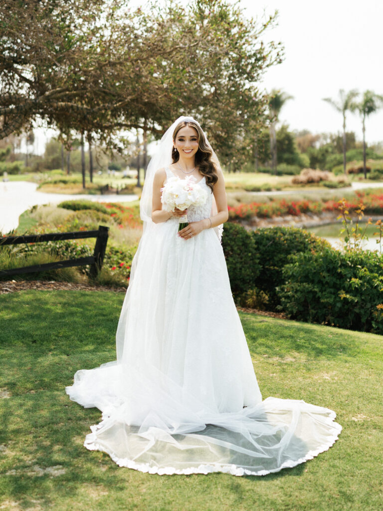 Radiant bride in A line wedding dress with long flowing veil during outdoor photoshoot